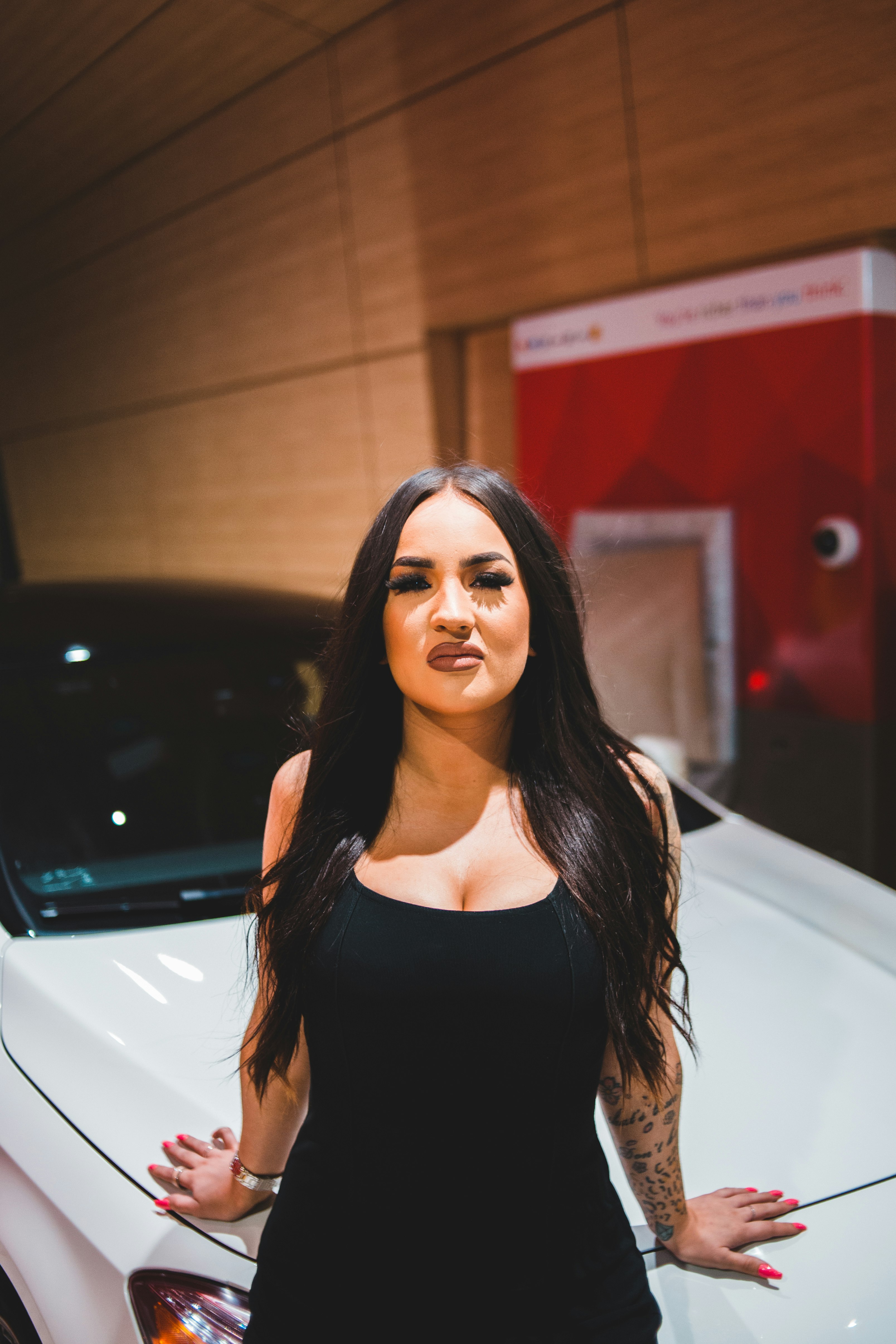 woman in black tank top standing beside white car